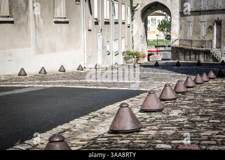 A row of metal spikes are on the street in Cognac France. They are in a row and are on the side of the road Stock Photo