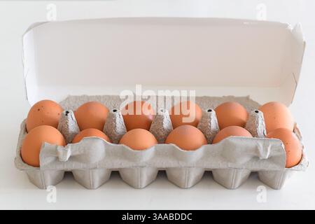 Fresh brown eggs in carton on kitchen countertop Stock Photo