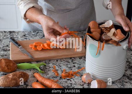 Woman peeling and cutting vegetables in kitchen and using composter for scraps Stock Photo