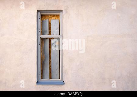 Minimalistic exterior wall with an old boarded up sealed closed window in a rustic frame. Perfect for urban decay themes and architectural design elem Stock Photo