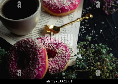 Close-up on a pink glaze with a white sprinkle. Doughnuts on the table with coffee. Stock Photo