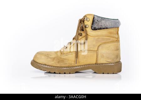 Single  vintage durable yellow leather hiking boot with laces in a worn look. One beige used military shoe with thick sole. Isolated on white backgrou Stock Photo