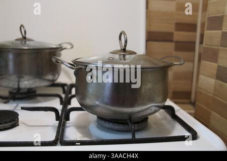 A metal saucepan stands on a gas stove. Kitchen, cooking. Stock Photo