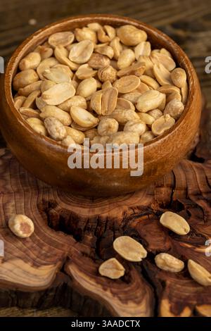kernels in a wooden bowl, fried yellow peanuts with a little salt on the table Stock Photo