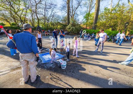 Children playing with soap bubbles in spring park under supervision of street performer. New York. USA. Stock Photo