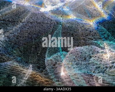 Sunlight passing through stained glass creates colorful rainbow reflections on a rough concrete wall, forming a vibrant and abstract pattern Stock Photo