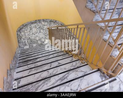 Marble staircase with curved landing and painted iron railing Stock Photo