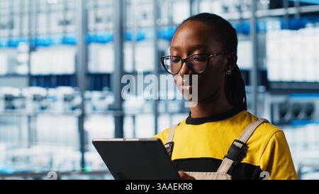 Smart factory engineer implements automated workflows and control systems using tablet, computerizing manual operations. Industry 4.0 worker integrates sensors into production using device, camera A Stock Photo
