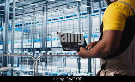 Industry 4.0 industrial plant specialist designs new robotic machines using CAD software on laptop. Smart factory technician using notebook to do tooling for automation equipment, camera A close up Stock Photo