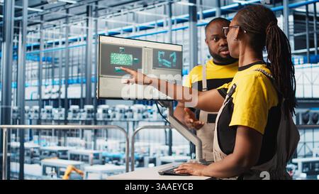 System administrators in smart factory collecting and analyzing data. Coworkers doing brainstorming, using tracking software in industrial plant equipped with advanced sensors, camera A close up Stock Photo