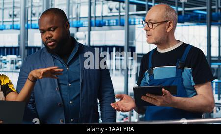 Manager supervising work done by engineering team in industry 4.0 industrial plant installing machinery. Supervisor overseeing smart factory coworkers doing brainstorming to calibrate IoT sensors Stock Photo