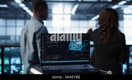 Artificial intelligence technology coding on laptop in data center with programmers in background employing machine learning models. Notebook used by AI IT experts, camera B close up Stock Photo