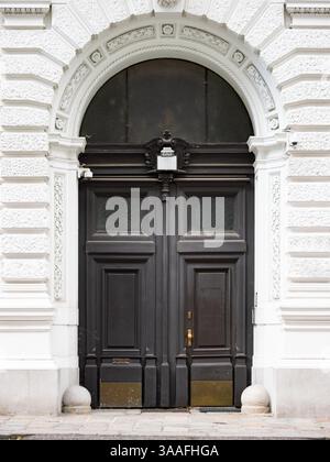 Empty double door close-up in an old town in Europe. Dark wooden entrance doors and a bright exterior wall. Close-up of the historical facade. Stock Photo