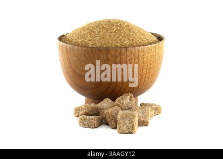 A wooden bowl is filled with granulated brown sugar, with sugar cubes scattered below, set against a clean white background. Stock Photo