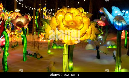 Street decor in form of glowing flowers on winter evening in snowdrifts. Winter Christmas decorations. Stock Photo