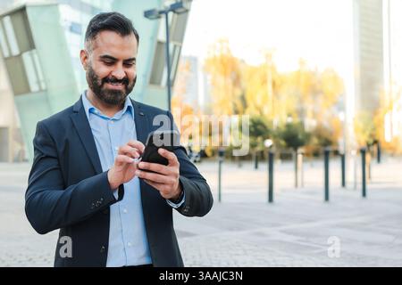 A successful businessman engaged in using a smartphone for effective communication, highlighting the importance of mobile technology in business interactions and personal connections in today's world. Stock Photo