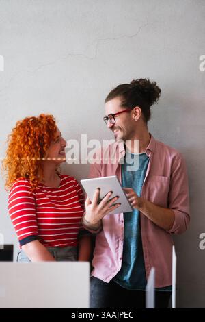 Friendly happy multiethnic coworker male and female having fun with tablet, working together Stock Photo