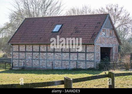 A modern barn built in a traditional half-timbered style with brick and wood in rural Lower Saxony, Germany, reflecting historic craftsmanship and des Stock Photo