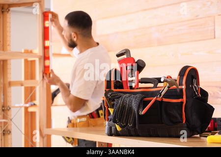 Male construction worker working with spirit level and bag of professional tools in office Stock Photo