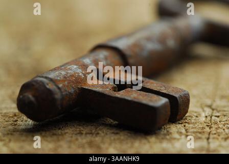 Close-up of old rusten key on woody surface Stock Photo