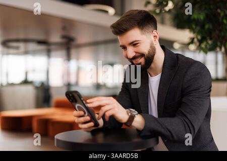 Successful financier investor works inside office at work, businessman in business suit uses telephone near window, man smiles and reads good news onl Stock Photo
