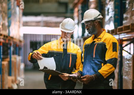 Warehouse workers working together, Staff inventory employee team in duty in storage warehouse building with safety suit Stock Photo