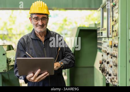 Portrait Senior Professional technician engineer supervisor male with heavy industry machine CNC in factory handle Laptop computer. Stock Photo