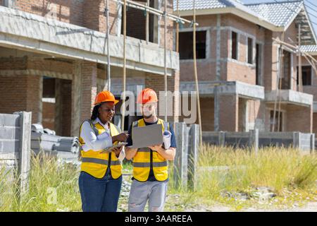 Construction worker talking with team African black women worker in construction site with laptop computer for process inspector teamwork. Stock Photo