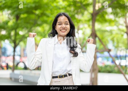 Happy success business women, Young businesswomen standing cheerful from good news successful people in green park outdoor. Stock Photo