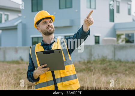 Construction Project manager, Worker happy smile, Caucasian engineer male standing wearing safety vest and helmet at construction site. Stock Photo
