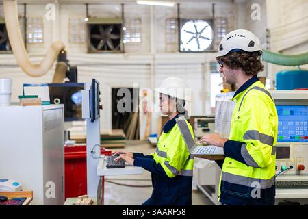 Professional technician engineer young teamwork staff workers control operate wood CNC machine together Stock Photo