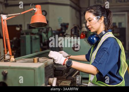 Engineer women working in Lathe shop with metal machinery lathe milling machine, expert skillful industry worker female. Stock Photo