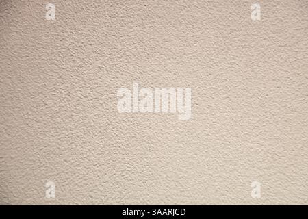 Close-up of a uniform textured beige wall with a stucco surface. The uniform pattern creates a neutral and minimalistic background suitable for design Stock Photo
