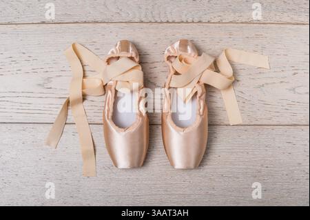 Ballet pointe shoes with satin ribbons lying on wooden floor represent the dedication and grace of classical dance Stock Photo