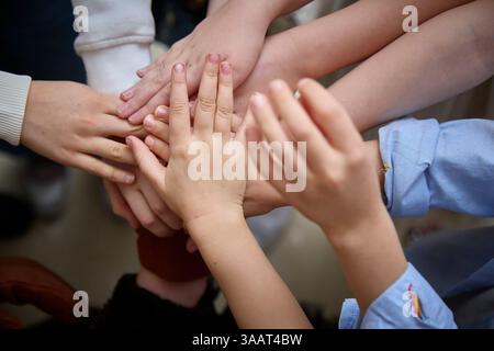 Group of diverse children's hands placed together in a united gesture of teamwork and collaboration, symbolizing unity, support, and cooperation among Stock Photo