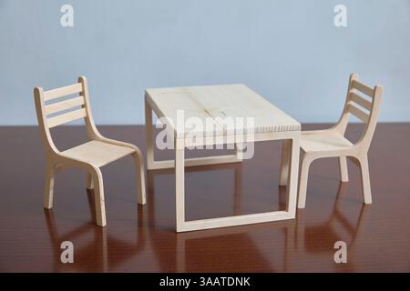 Simple miniature wooden table with two matching chairs against a neutral background. Highlighting craftsmanship and minimalist design in a tabletop se Stock Photo
