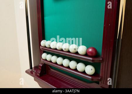 Billiard scoreboard showcasing a collection of numbered white balls and a single red ball on a green felt background, neatly arranged on wooden shelve Stock Photo