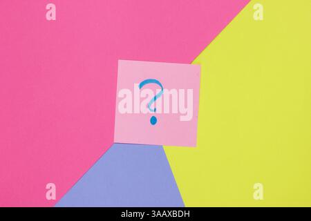 Memo piece of paper with drawn question marks on colored  background. Top view. Minimalism Stock Photo