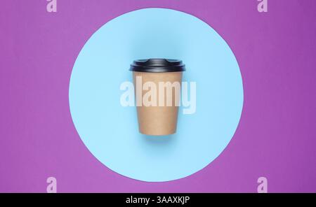 Сraft сardboard сoffee сup on purple background with blue pastel circle. Top view Stock Photo