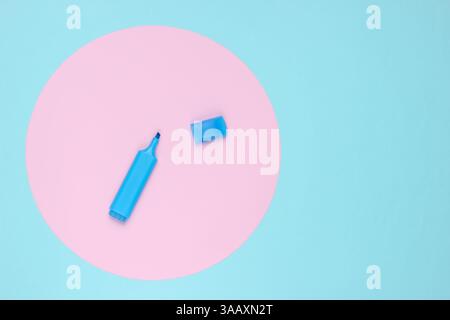 Felt-tip pen on blue background with pink pastel circle. Top view. Stock Photo