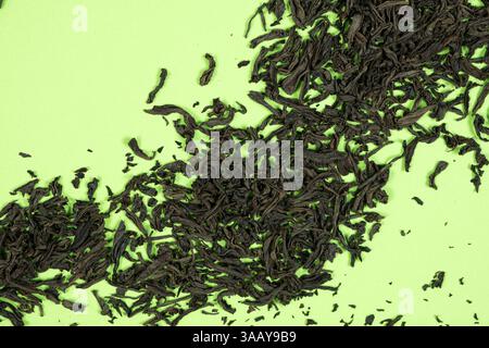 Top view of dried black tea leaves on green background. Stock Photo