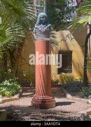 Ajaccio, Corsica, France July 8, 2024: Bonaparte museum garden in Rue Saint Charles, a narrow alley. Bust statue of Napoleon as a kid placed on a pill Stock Photo