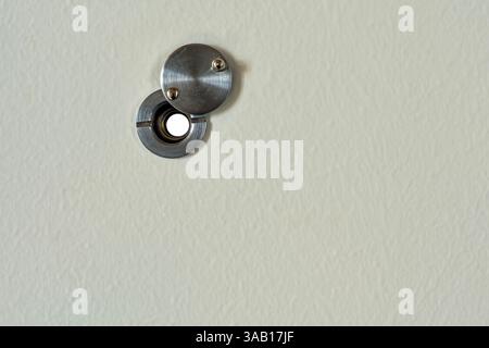 The cover of a metal peephole is opened on the interior side of a door Stock Photo