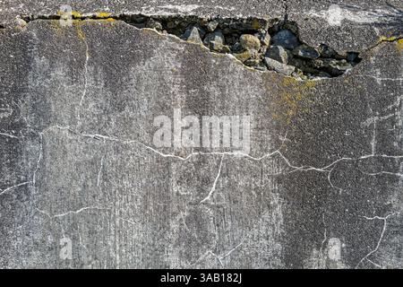 Small and large cracks are visible in an old concrete wall Stock Photo
