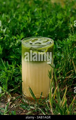 Iced green tea matcha latte in a glass with green background Stock Photo