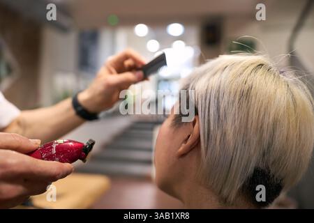 Hairdresser cutting short blonde hair of young woman in salon Stock Photo