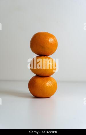 3 clementines stacked to make a pyramid on a white background. Stock Photo