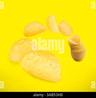 Raw potato slices transforming into crispy chips in air on yellow background Stock Photo