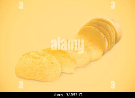 Raw potato slices transforming into crispy chips on pale orange background Stock Photo