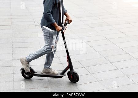 Black guy having pleasant ride on electric kick scooter Stock Photo